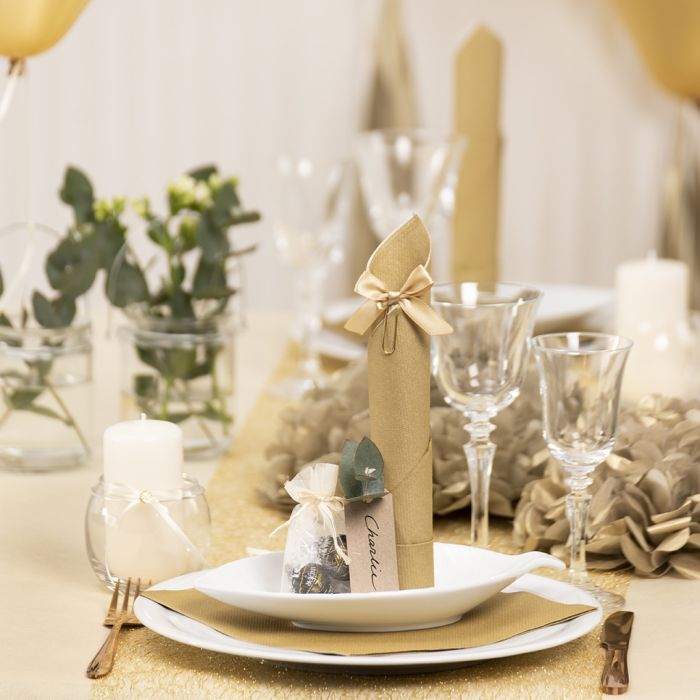 Décorations de table dorées avec des fleurs en papier, des ballons, une serviette pliée en forme de tour et des cartes de place