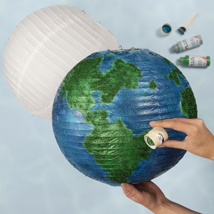 Un globe fabriqué à partir d'une lampe en papier de riz, décoré avec de la peinture artisanale et des paillettes bio.