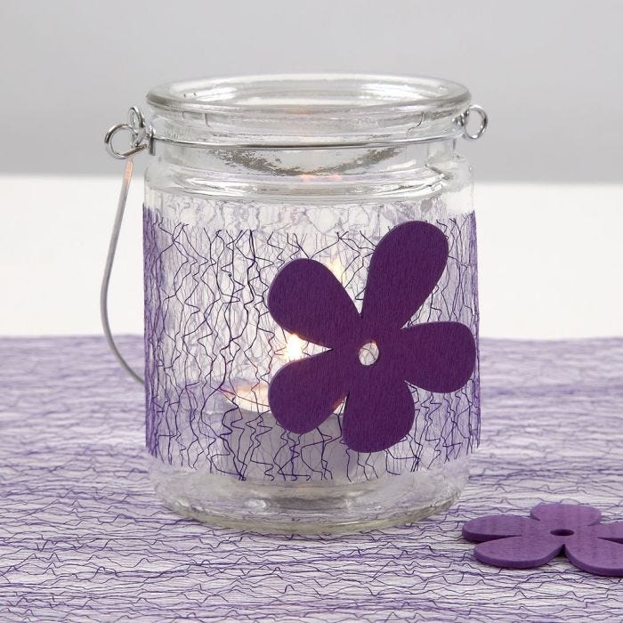 Un bougeoir avec une ceinture de filet violette et une fleur en bois
