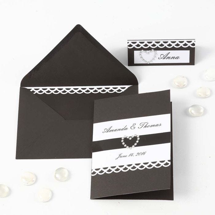 Une invitation et un marque-place noirs avec du ruban en papier dentelle blanc