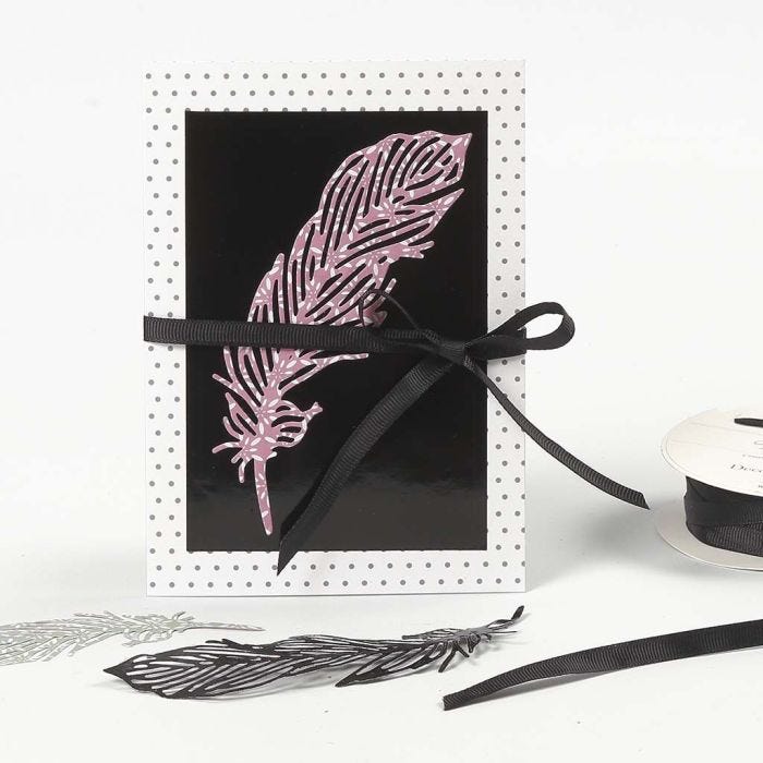 Une carte avec motifs décorée d'une plume en papier découpée