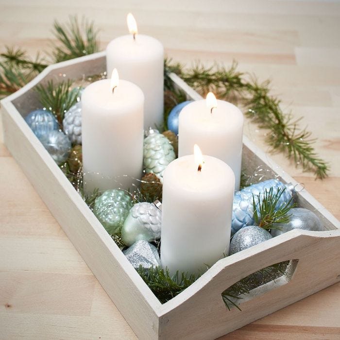 Un plateau avec quatre bougies et des boules de Noël en verre et en terre cuite peintes.