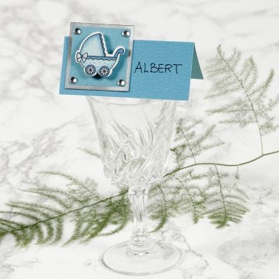 Un marque-place décoré d'un landau pour un baptême