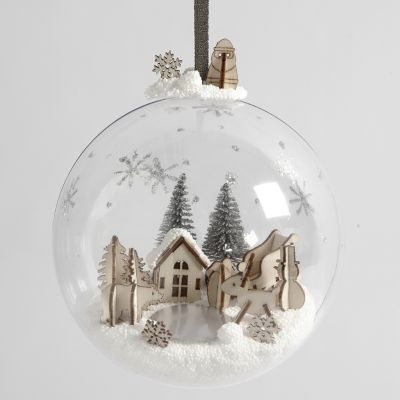 Un monde miniature en pâte à modeler foam et figurines en bois à l’intérieur d’une boule de Noël