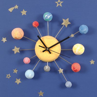 Une horloge murale décorée avec des planètes en pâte Silk Clay
